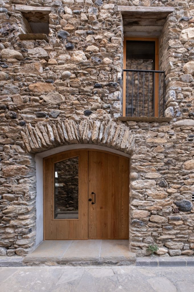Puerta de madera en arco de piedra en la entrada de la borda