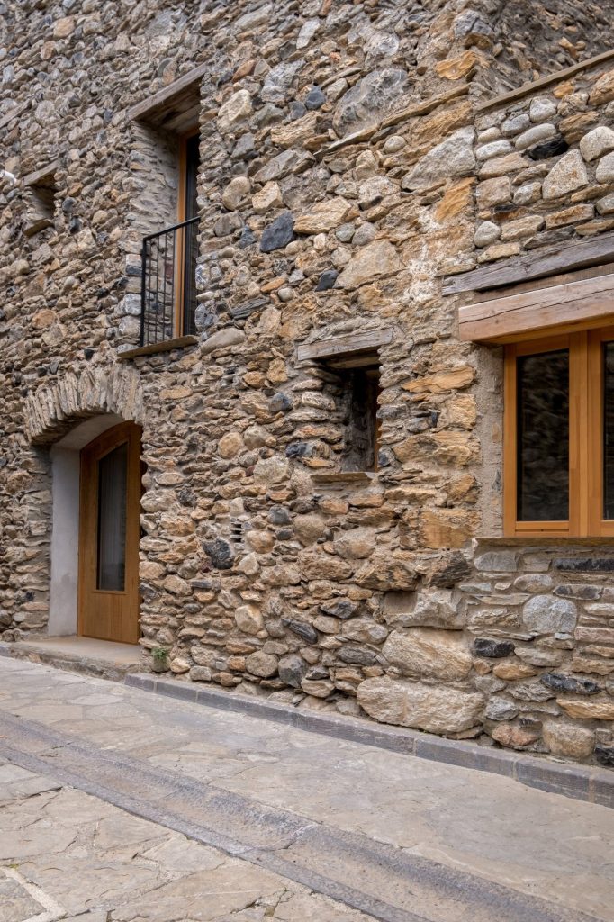 Fachada de mampostería con carpinterías de madera al callejón