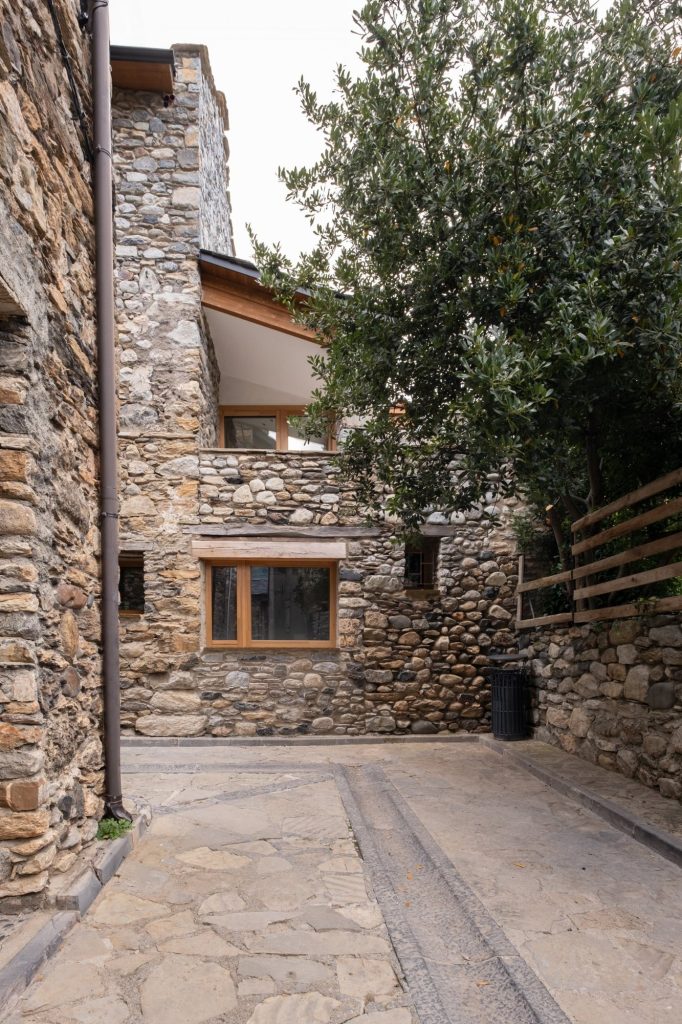 Patio trasero de la vivienda con muros de piedra y arbolado