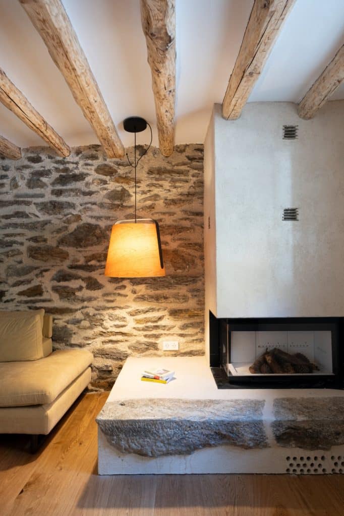 Chimenea y muro de piedra con lámpara de madera