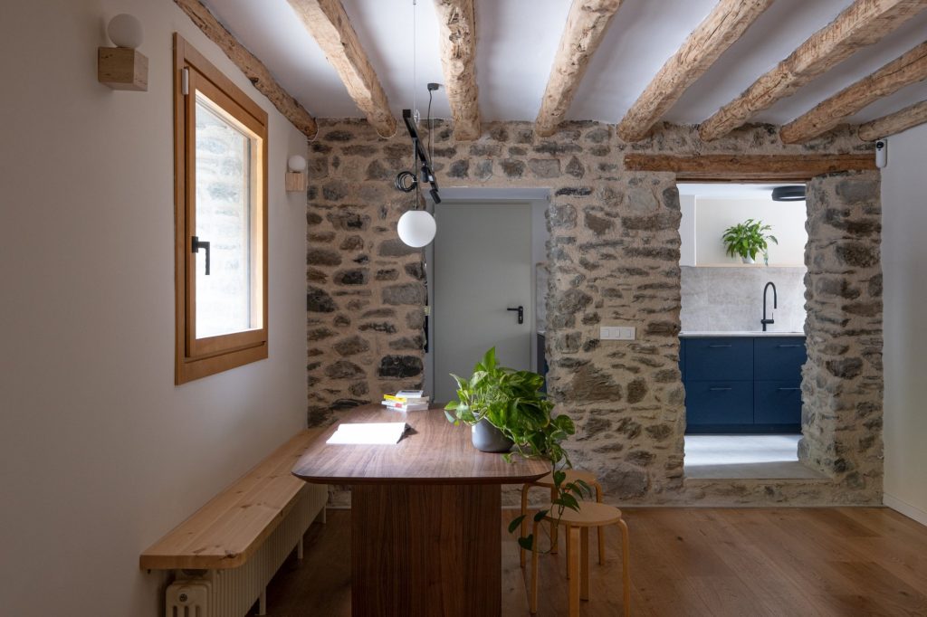Comedor con muros de piedra y acceso a la cocina