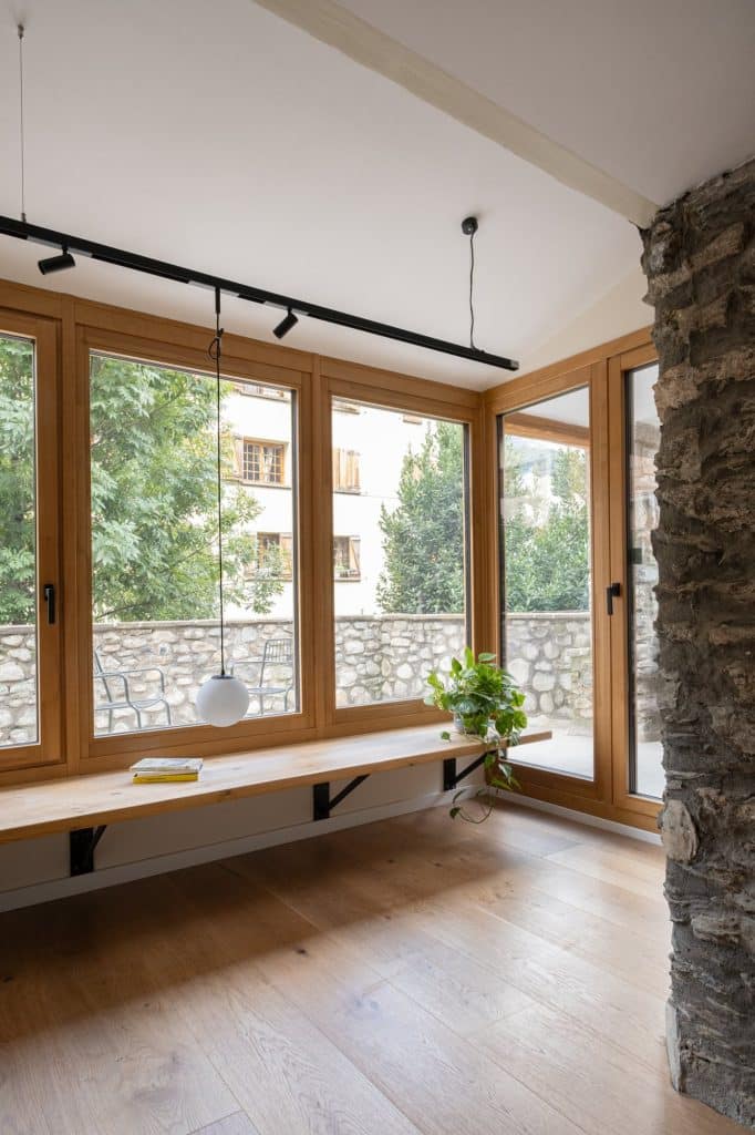 Espacio acristalado con banco de madera junto a la terraza