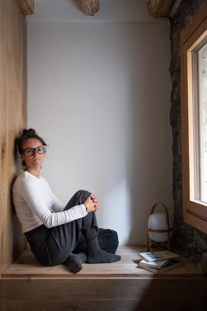 Blanca Rupérez, arquitecta, sentada en un banco de madera junto a una ventana