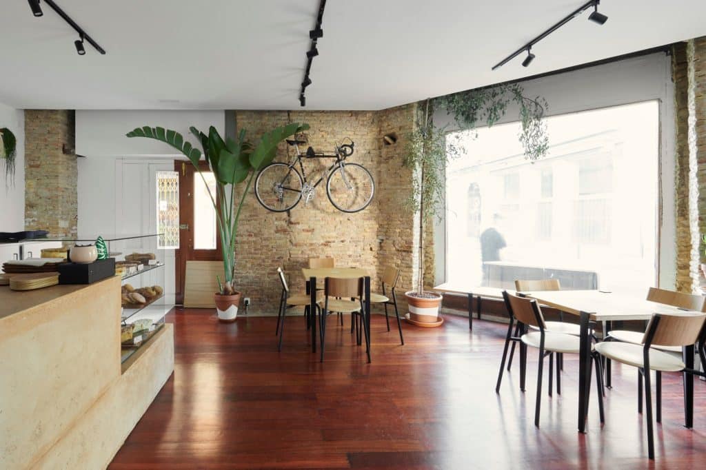 Sala con muro de ladrillo recuperado, gran ventanal y pavimento de madera noble