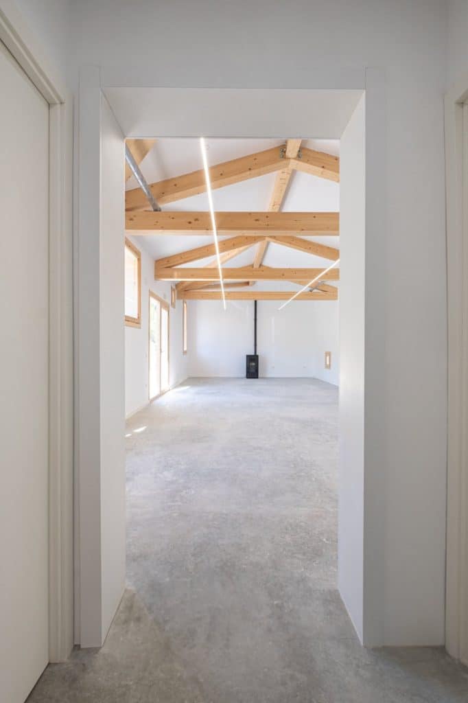 Vista de la sala expositiva desde el acceso, con cerchas de madera y losa de hormigón vista