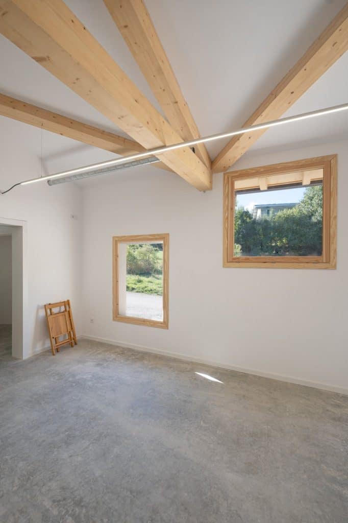 Ventanas a sur con carpintería de madera y cerchas en la sala expositiva