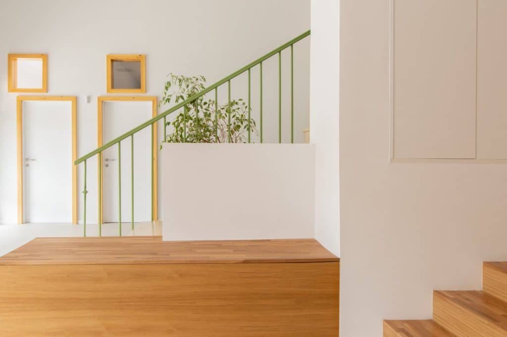 Banco de madera y barandilla verde de la escalera en el vestíbulo