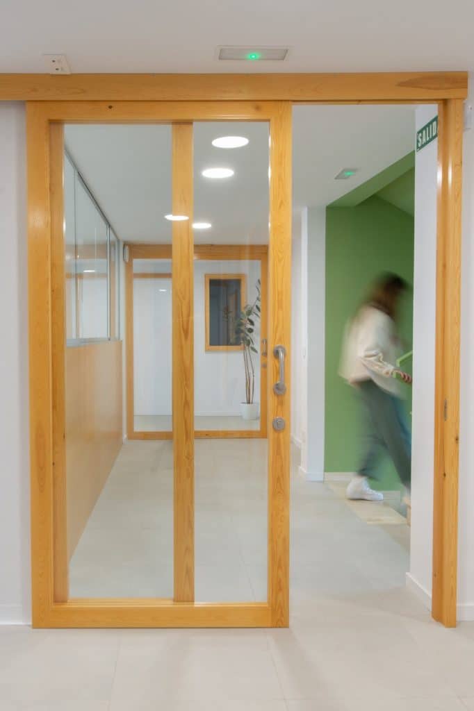 Puerta corredera de madera y vidrio junto a la escalera verde