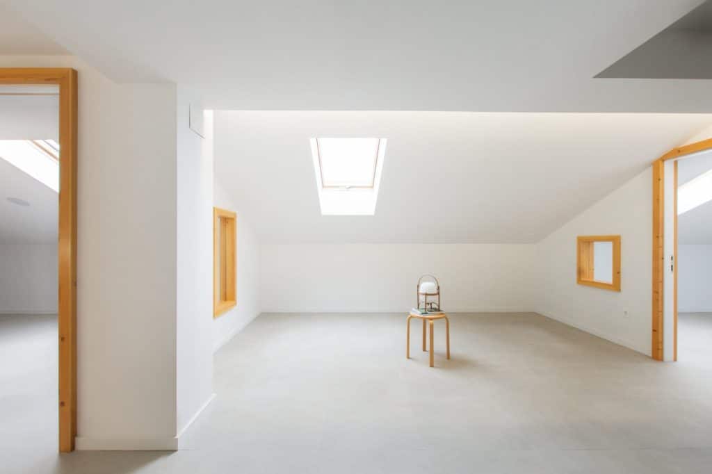 Sala bajo cubierta con lucernario y huecos enmarcados en madera