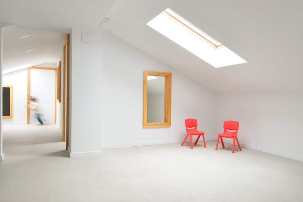 Sala bajo cubierta con lucernario y sillas rojas
