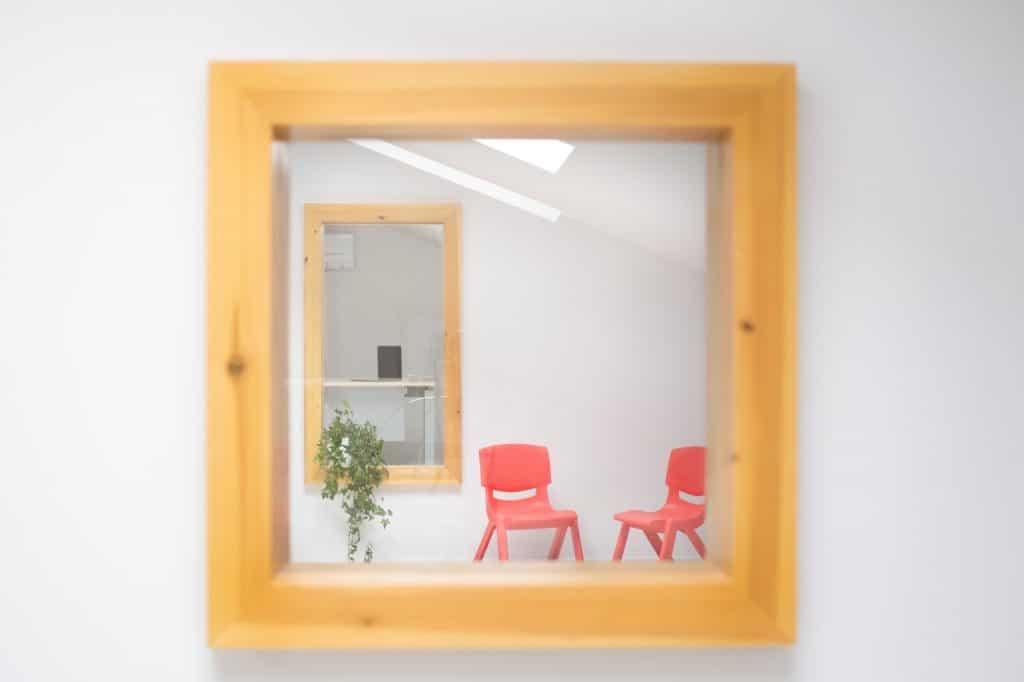 Hueco interior enmarcado en madera con sillas rojas al fondo