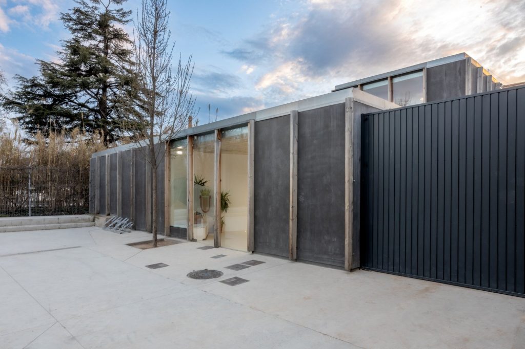 Fachada de la ludoteca de Ricla con paneles oscuros y pilares de madera