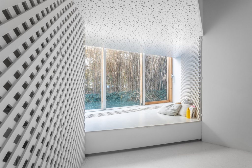 Ventana-banco con cojines, techo perforado y celosía blanca