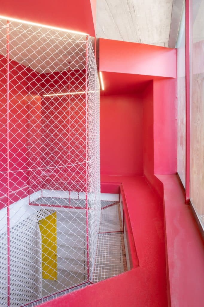Escalera roja con malla metálica y puerta amarilla al fondo
