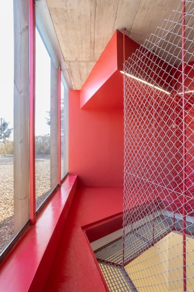 Ventana-banco roja en la planta alta con malla metálica
