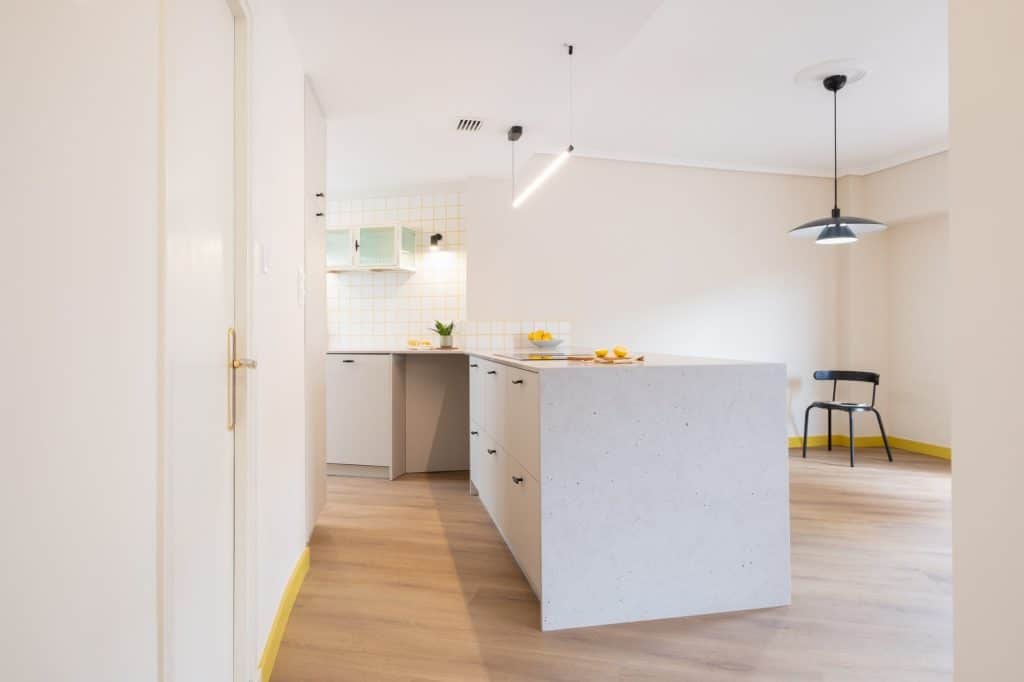 Cocina abierta al comedor con península de frente gris y lámpara negra
