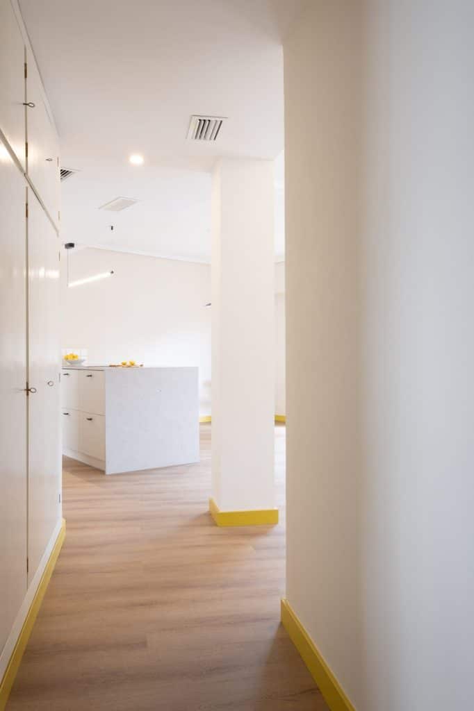 Pasillo de acceso con rodapié amarillo y vista a la cocina