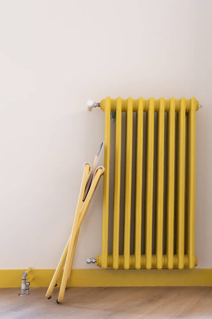 Radiador de columnas pintado en amarillo con revistero plegable apoyado