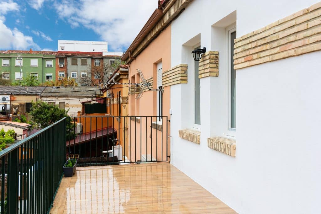 Fachada blanca con detalles de ladrillo caravista y terraza