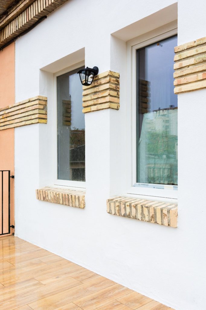 Ventanas con alféizares y bandas de ladrillo caravista en la fachada